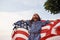 Beautiful green tree. Patriotic female kid with American Flag in hands. Against cloudy sky