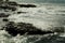 Beautiful grey sea stormy waves splash against black stony shore