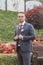 A beautiful groom in a suit stands in a blooming garden