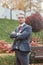 A beautiful groom in a suit stands in a blooming garden