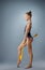 Beautiful gymnast girl in sportswear, rhythmic gymnastics element with mace on gray background