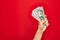 Beautiful hand of man holding bunch of dollar banknotes over isolated red background