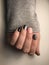 Beautiful hands with manicure nails in grey knitted sweater sleeve