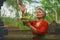 Beautiful and happy Asian Indonesian woman dressed in traditional Balinese religious custom holding incense stick and flowers