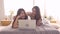 Beautiful happy Asian lesbian couple or friends are wear pajamas using laptop or computer to video call with friends on bed.