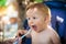 Beautiful happy baby boy eating porridge food, with a spoon