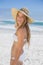 Beautiful happy blonde on the beach in white bikini and sunhat