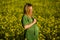 Beautiful and happy blonde expecting mother in green dress, smiles in the middle of a yellow flowery field.