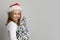 Beautiful happy child girl in Santa hat holding snowy green Christmas tree on white background with copy space