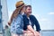Beautiful happy couple enjoying sailing together, sitting on the side of sailboat, yacht. Selective focus on handsome man