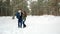 Beautiful happy couple in love walking in the forest, guy hugs girl,the young people out for a walk in the winter