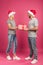 beautiful happy couple in santa hats gifting christmas present