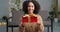 Beautiful happy curious girl african american woman sitting on floor at home in cozy living room holding red gift box