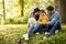 Beautiful happy family is having fun with bichon dog under the tree outdoors