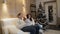 Beautiful happy family of three on the sofa smiling and talking by the Christmas tree on Christmas night.
