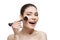 Beautiful happy girl applying blush with brush