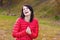 Beautiful, happy girl with perky smile in red jacket is in the forest