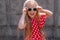 Beautiful happy girl in a red polka dot dress smiling on on concrete wall background. Cute joyful child with long hair