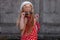 Beautiful happy girl in a red polka dot dress smiling on on concrete wall background. Cute joyful child with long hair