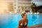 Beautiful happy girl with a smile in a hotel pool in a southern tropical resort