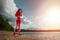 A beautiful, happy girl in a tracksuit runs along the path of a lake or sea. The concept of a healthy lifestyle, cardio workout.