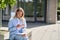 Beautiful happy girl university student using mobile phone sitting outside.