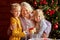 Beautiful happy granchildren and grandmother congratulating each other with christmas
