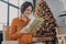 Beautiful happy Italian woman sitting with gift next to festively decorated Xmas tree at home