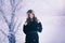 Beautiful happy laughing young woman wearing winter hat gloves covered with snow flakes.