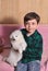 Beautiful happy little boy holding cute fluffy white samoyed puppy at home vertical shot portraite Love pets dog animal