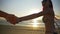 Beautiful happy lovers running in slow motion on a beach towards the sea at sunrise