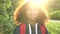 Beautiful happy mixed race African American girl teenager female young woman hiking with red backpack in the country at sunset