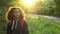 Beautiful happy mixed race African American girl teenager female young woman hiking with red backpack in the country at sunset