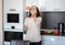 Beautiful happy modern charming elderly woman in glasses in the kitchen throwing an orange up, healthy eating concept