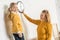 beautiful happy mother and daughter hanging clock on wall during relocation