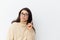 a beautiful, happy, neat woman in a beige turtleneck sweater and black-rimmed glasses, standing on a light background