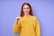 beautiful happy redhead woman in yellow stylish sweater demonstrating letter T