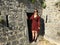 A beautiful happy smiling young tourist standing beside one of the doorways or entrances to the ancient stone Klis Fortress