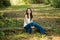 A beautiful happy teenage brunette girl sitting outdoors on a log hapy and smiling with copy space