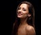 Beautiful happy toothy contagious smiling woman with brown hair looking happy on black background with empty copy space. Closeup