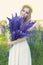 Beautiful happy ulybchvaya girl in a white sundress with a bouquet in the hands of lupine and yellow wreath of roses in her