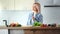 Beautiful happy vegetarian woman smiling dancing eating fresh vegetables at kitchen medium shot