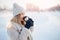 Beautiful happy woman outdoor winter. Laughing girl with hot drink tea or coffee with snowfall