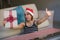 Beautiful and happy woman in Santa hat holding Christmas present box with red ribbon smiling excited at home living room receiving