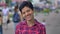 Beautiful happy woman with short hair smiling with teeth and looking at camera, standing on street in urban city