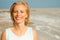 Beautiful happy woman smiling with closed eyes on the sea shore, closeup portrait