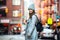 Beautiful happy woman walking on city street wearing casual grey coat and hat with a bag