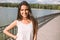 Beautiful happy young brunette woman with beautiful smile, with a windy long hair, on park background with a lake. Loo