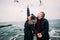 Beautiful happy young couple softly holding hands and posing on the pier. Seagulls at background. Romantic honeymoon