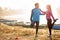 Beautiful happy young couple stretching by the lake in the early morning, warming up for jogging